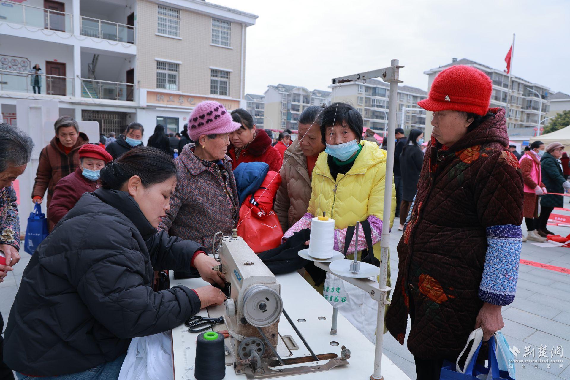 衣物縫補(bǔ)攤前，志愿者飛針走線為居民修補(bǔ)破損衣物.jpg.jpg